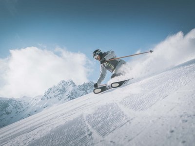 Hotel in Ladurns – perfekt für den Winterurlaub! Skifahrer fährt mit hoher Geschwindigkeit die Piste hinunter bei klarem Himmel