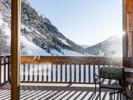 Familienhotel in Sterzing: hoi und herzlich willkommen! Balkon mit Stuhl und Tisch mit Blick auf schneebedeckte Berge im Sonnenlicht