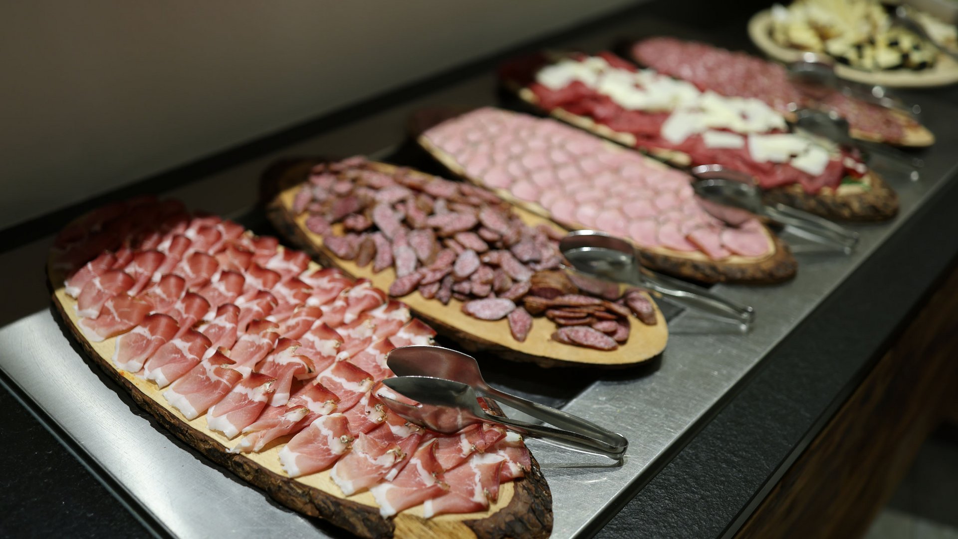 Genuss aus Pflersch: Hotel Panorama Brett mit Aufschnitt, Essiggurken, Tomaten und Käse auf Holztisch im Freien