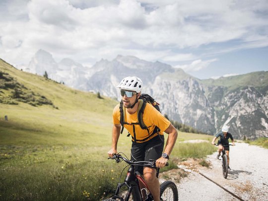 Pflerschtal: accommodation for biking holidays Two cyclists wearing helmets biking on mountain trail in green landscape