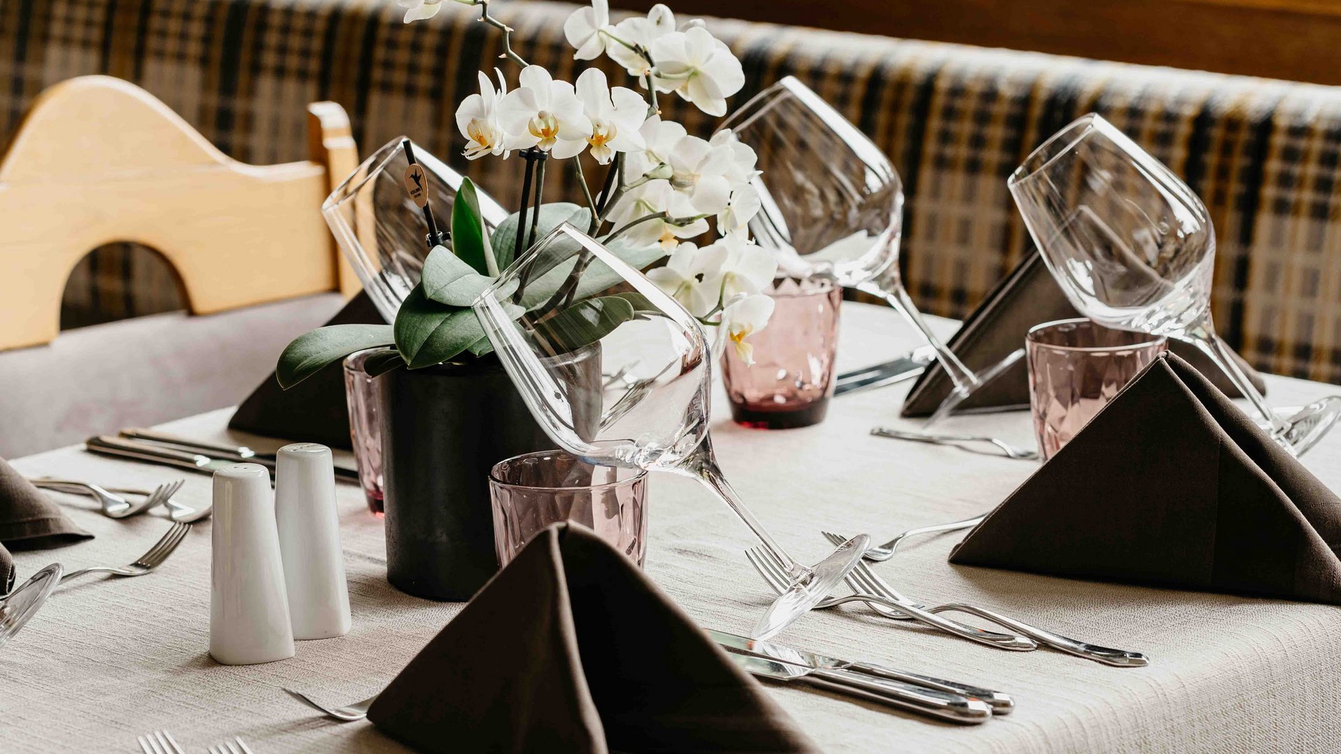 Familienhotel in Sterzing: hoi und herzlich willkommen! Eleganter gedeckter Tisch mit weißen Orchideen und Weingläsern