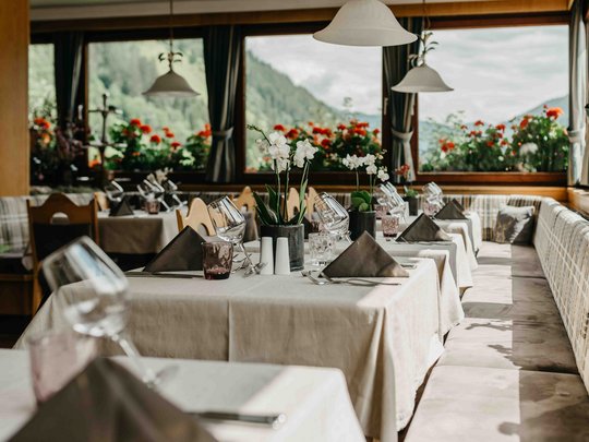 Familienhotel in Sterzing: hoi und herzlich willkommen! Elegantes Restaurant mit gedeckten Tischen und Bergblick am Fenster