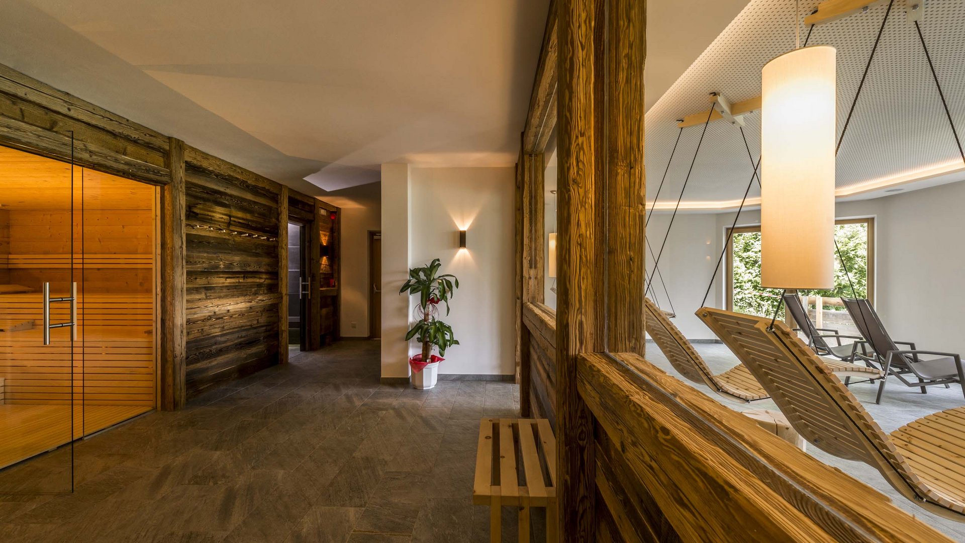 Familienhotel in Sterzing: hoi und herzlich willkommen! Heller Wellnessbereich mit Sauna, Holzlehnsesseln und moderner Beleuchtung