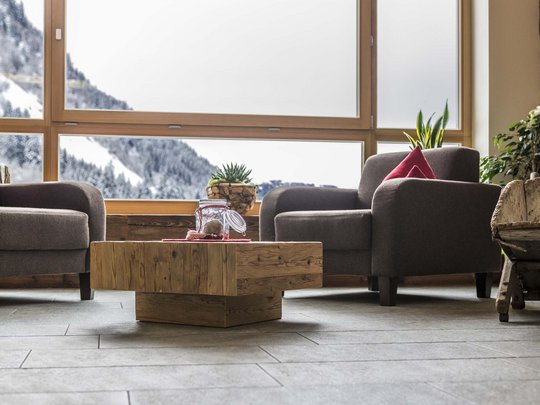 Familienhotel in Sterzing: hoi und herzlich willkommen! Gemütlicher Sitzbereich mit Blick auf verschneite Berge durch großes Fenster