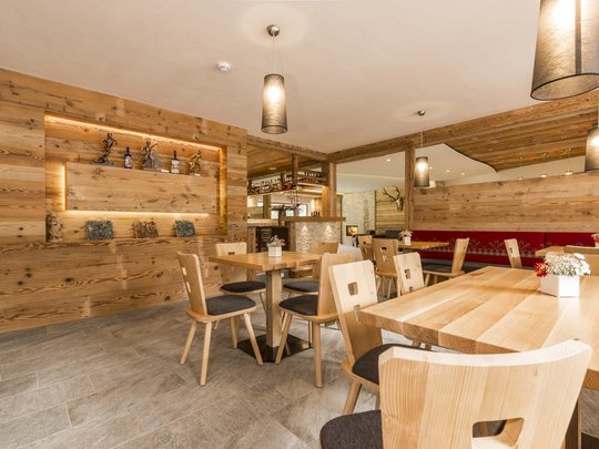 Familienhotel in Sterzing: hoi und herzlich willkommen! Gemütlicher moderner Gastraum mit Holzmöbeln und warmem Licht