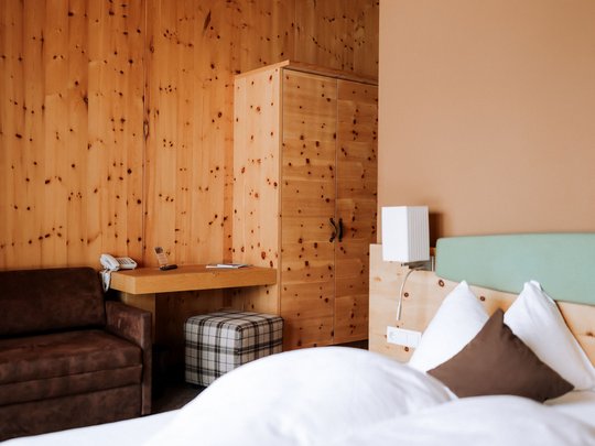 Familienhotel in Sterzing: hoi und herzlich willkommen! Hotelzimmer mit Holzwänden, Bett, Sofa und Schrank