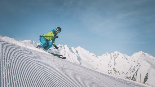 Familienhotel in Sterzing: hoi und herzlich willkommen! Skifahrer auf präparierter Piste vor verschneiten Bergen