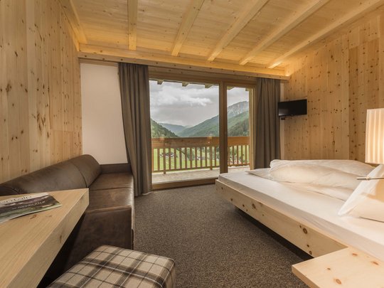 Familienhotel in Sterzing: hoi und herzlich willkommen! Gemütliches Holzzimmer mit Balkon und Bergblick