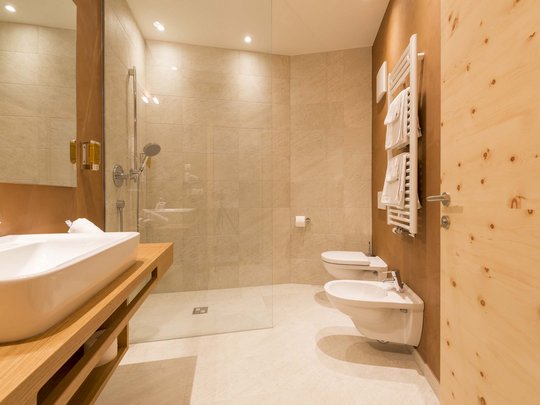 Familienhotel in Sterzing: hoi und herzlich willkommen! Modernes Badezimmer mit Holz und beiger Fliesendusche